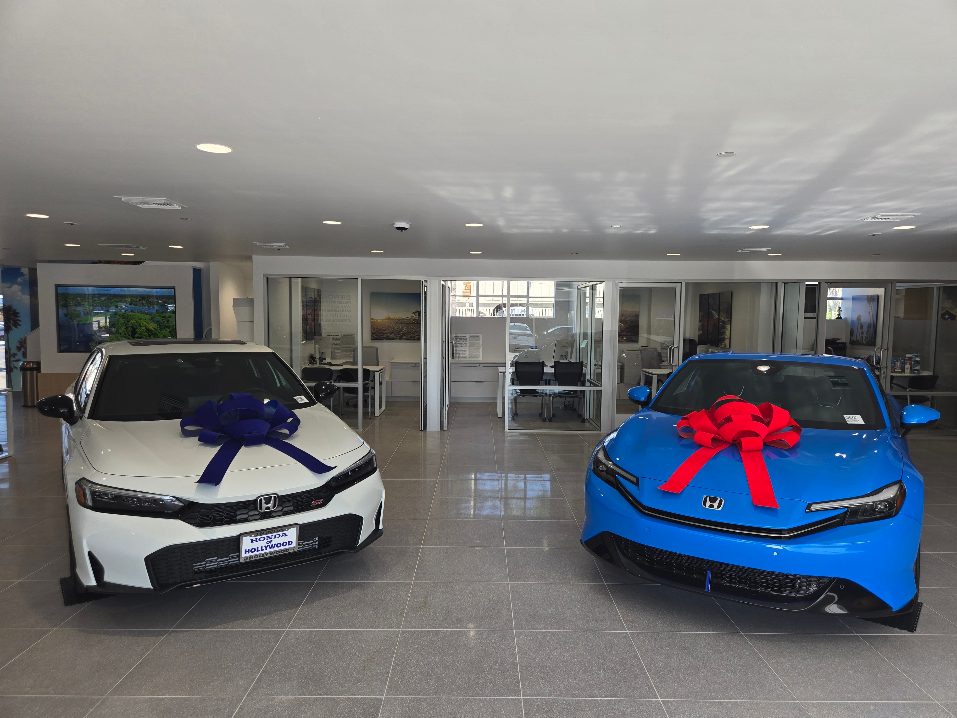 Dealership employee showing customers cars on showroom floor.